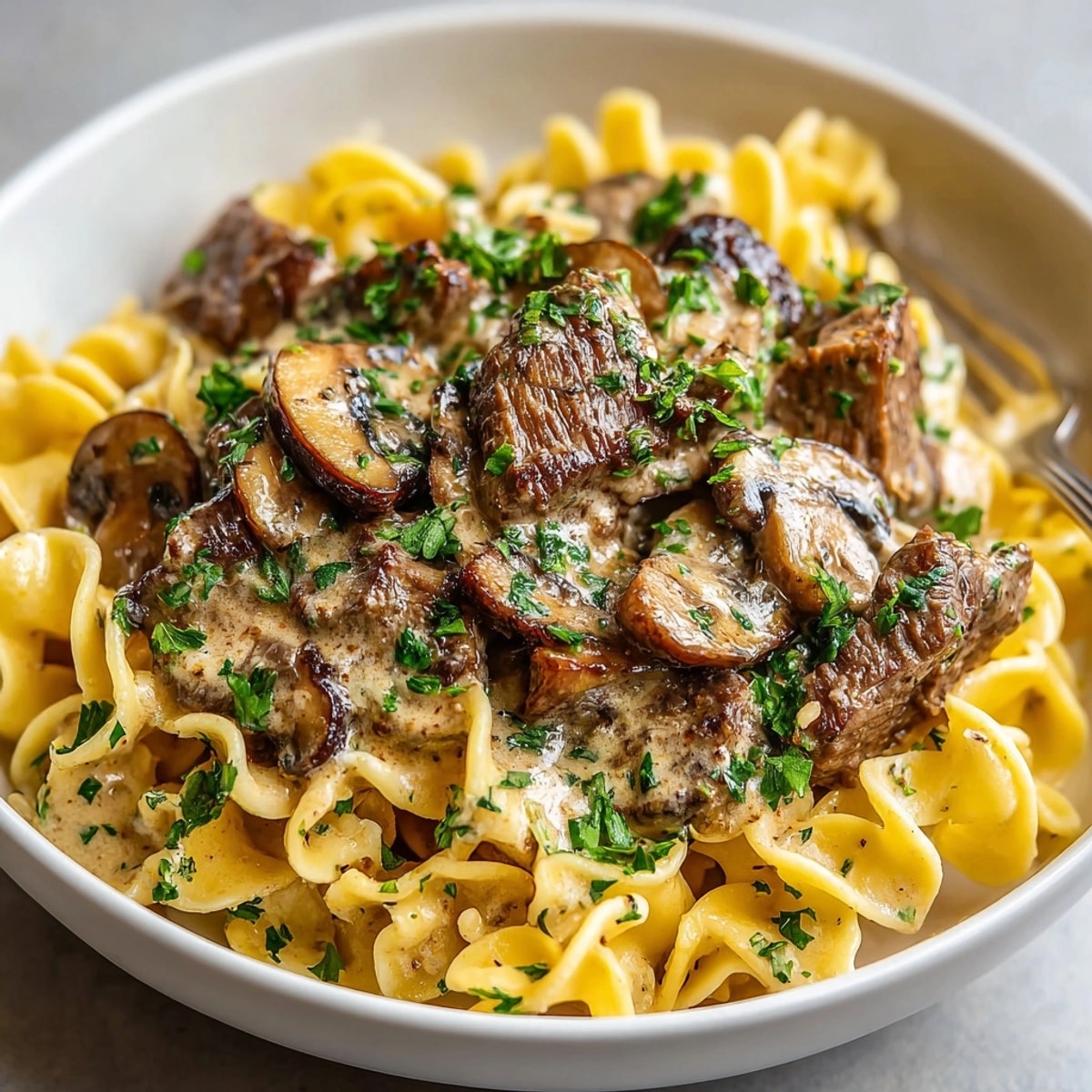 Creamy Beef and Mushroom Stroganoff served over fluffy, golden egg noodles provides a hearty, satisfying meal.