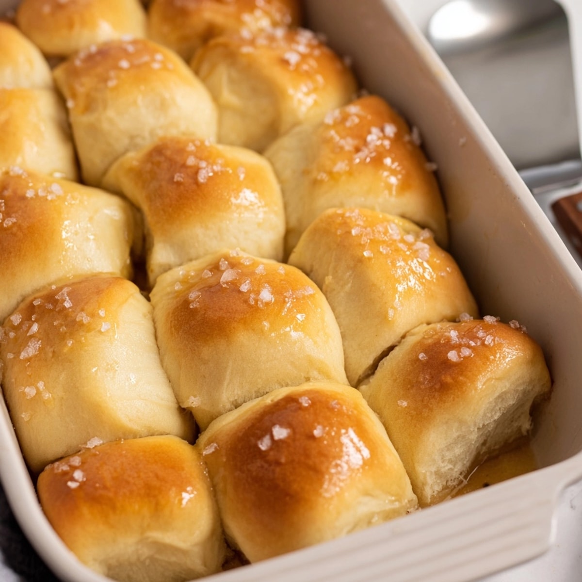 Freshly baked Salted Honey Butter Parker House Rolls, brushed with glaze and sprinkled with sea salt.