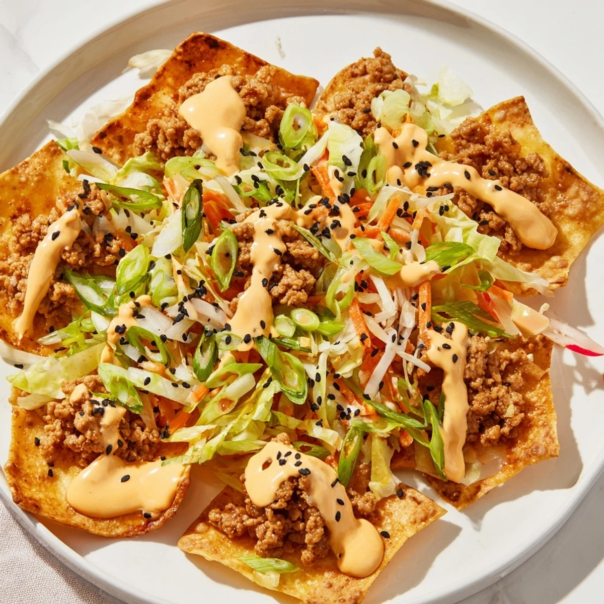 Crispy Japanese Gyoza Nachos topped with spicy sriracha mayo and fresh veggies.  