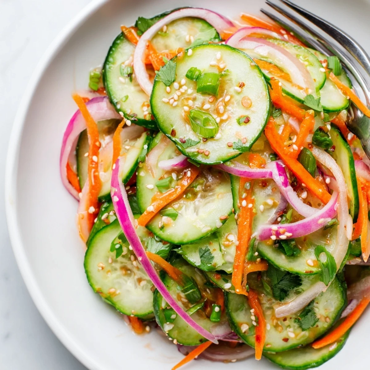 Refreshing cucumber salad remix with sesame oil and fish sauce drizzled over vibrant veggies.  