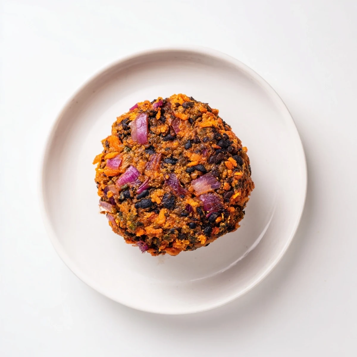 A close-up of a perfectly cooked, textured black bean burger, ready to be eaten on a bun.