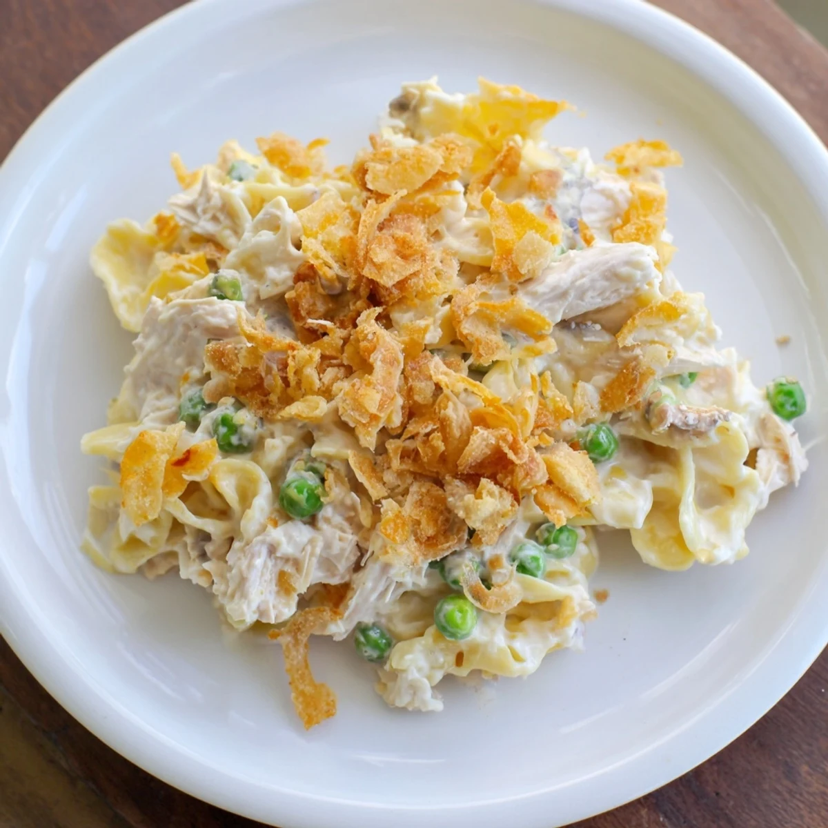Warm, creamy Tuna Noodle Casserole with visible peas and cheese, perfect for a cozy dinner.