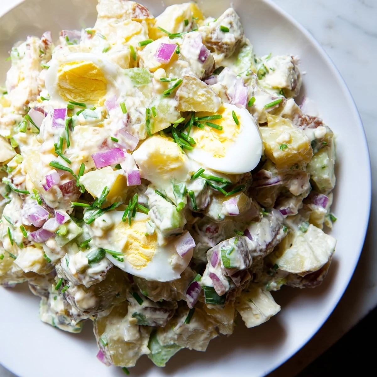 A close-up of creamy chopped egg and potato salad, ready to be enjoyed as a side dish.
