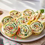 Festive Cozy Scarf Holiday Pinwheel Wraps, perfect appetizer with creamy filling and vibrant veggie colors arranged.