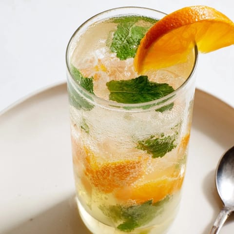 Homemade probiotic soda mocktail garnished with orange slices and fresh mint leaves.  