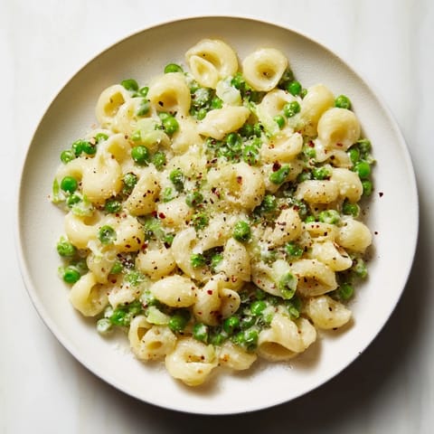 Close-up of golden Macaroni & Peas, tossed with peas and Parmesan cheese.
