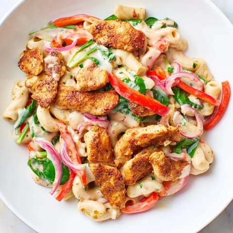 A close-up of creamy Cajun Dirty Snow Chicken Pasta, showcasing tender chicken pieces and perfectly cooked pasta.