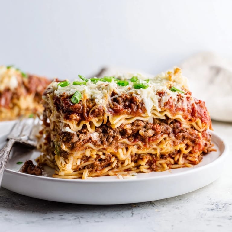 A comforting Spicy Ramen Lasagna shows bubbling cheese and savory layers on a dining table.  